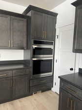 Kitchen with light hardwood / wood-style floors, stainless steel double oven, and dark brown cabinetry