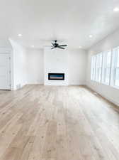 Unfurnished living room with ceiling fan and light wood-type flooring