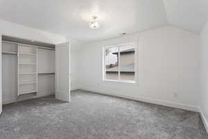 Unfurnished bedroom featuring a closet, carpet floors, and vaulted ceiling