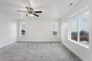 Spare room featuring a wealth of natural light, carpet, and ceiling fan