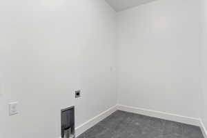 Laundry area with hookup for an electric dryer and dark tile floors