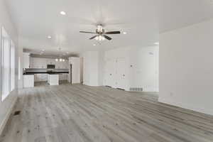 Unfurnished living room with ceiling fan and light hardwood / wood-style flooring