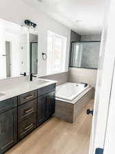 Bathroom with hardwood / wood-style floors, tiled tub, and double sink vanity