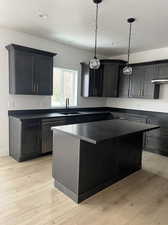 Kitchen with light hardwood / wood-style flooring, a kitchen island, stainless steel dishwasher, sink, and a textured ceiling