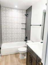 Full bathroom with tiled shower / bath, hardwood / wood-style floors, toilet, and vanity