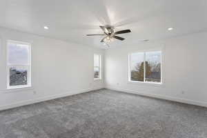 Empty room with plenty of natural light, ceiling fan, and carpet floors