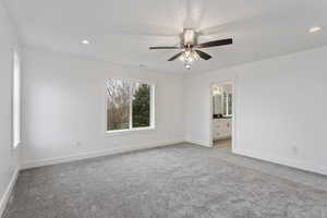 Unfurnished bedroom with light carpet, ceiling fan, and ensuite bath