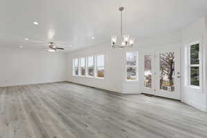 Unfurnished dining area with light hardwood / wood-style flooring and ceiling fan with notable chandelier