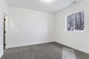 Spare room featuring dark colored carpet