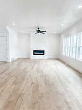 Unfurnished living room with ceiling fan and light hardwood / wood-style flooring