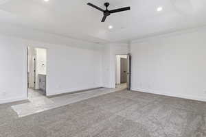 Carpeted empty room featuring a raised ceiling and ceiling fan