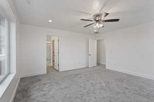 Unfurnished bedroom with ensuite bathroom, ceiling fan, and carpet floors