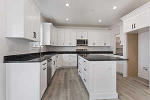 Kitchen with a center island, light hardwood / wood-style floors, white cabinetry, stainless steel appliances, and sink