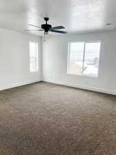 Unfurnished room featuring ceiling fan, carpet floors, and a textured ceiling