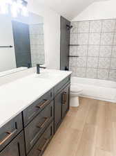 Full bathroom featuring tiled shower / bath combo, hardwood / wood-style floors, toilet, and vanity