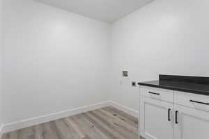 Laundry area with light hardwood / wood-style floors, washer hookup, electric dryer hookup, and cabinets