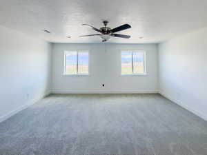 Carpeted empty room featuring a textured ceiling and ceiling fan