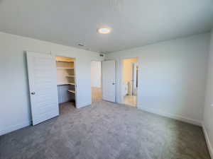 Unfurnished bedroom featuring carpet, a closet, and a spacious closet