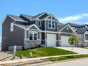 Craftsman-style home featuring a garage and a front lawn