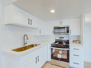 Kitchen featuring light hardwood / wood-style flooring, stainless steel appliances, sink, backsplash, and white cabinetry