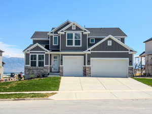 Craftsman inspired home featuring a garage, a mountain view, and a front yard