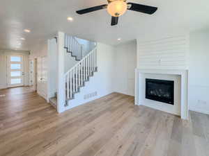 Unfurnished living room with a textured ceiling, ceiling fan, and light hardwood / wood-style floors