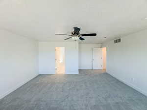 Unfurnished bedroom featuring ensuite bath, a textured ceiling, ceiling fan, and carpet flooring