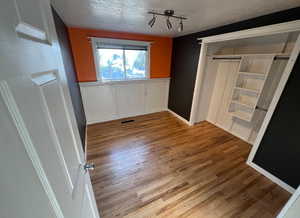 Spare room featuring light wood-type flooring, track lighting, and a textured ceiling