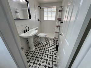 Bathroom featuring tile walls, toilet, a shower with curtain, and tile patterned floors