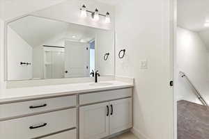 Bathroom featuring lofted ceiling and vanity