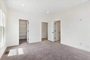 Unfurnished bedroom with a closet, carpet flooring, and a spacious closet