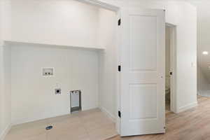 Laundry area with hookup for an electric dryer, light wood-type flooring, and washer hookup