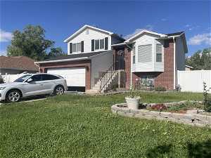 Split level home with a front lawn and a garage