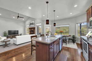 Kitchen featuring a fireplace, dark hardwood / wood-style flooring, hanging light fixtures, sink, and a kitchen island with sink