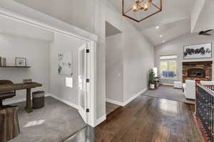 Corridor with a chandelier, vaulted ceiling, and dark hardwood / wood-style flooring