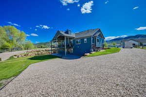 Rear view of property with a patio area, an outdoor structure, a mountain view, and a yard