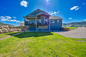 Back of property featuring a patio, a yard, a mountain view, and a balcony