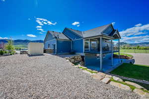 View of front of house with a front yard, a storage unit, a mountain view, and a patio