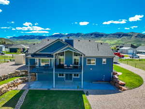 Back of house featuring a patio, a mountain view, and a lawn