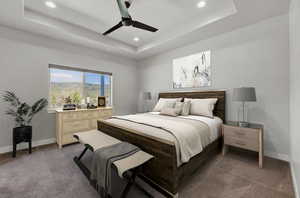 Bedroom with a tray ceiling, dark colored carpet, and ceiling fan