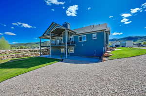 Rear view of property featuring a mountain view, a lawn, a balcony, and a patio area