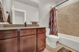 Full bathroom featuring shower / bath combo with shower curtain, tile flooring, vanity, and toilet