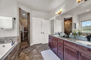 Bathroom with independent shower and bath, dual sinks, tile floors, and large vanity