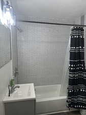 Bathroom featuring shower / bath combo, a textured ceiling, and vanity