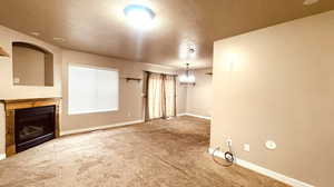 Unfurnished living room with a textured ceiling and carpet flooring