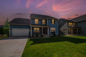 View of front of property with a garage and a yard