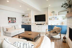 Living room featuring beam ceiling, light wood-type flooring, and built in features