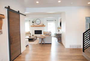 Living room with a barn door, plenty of natural light, and light hardwood / wood-style floors