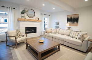 Living room featuring beam ceiling, a fireplace, light hardwood / wood-style flooring, and plenty of natural light