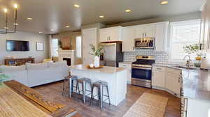 Kitchen featuring sink, a center island, stainless steel appliances, and white cabinetry